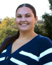 Caitlin, wearing a navy and white striped sweater, as well as gold hooped earrings. 